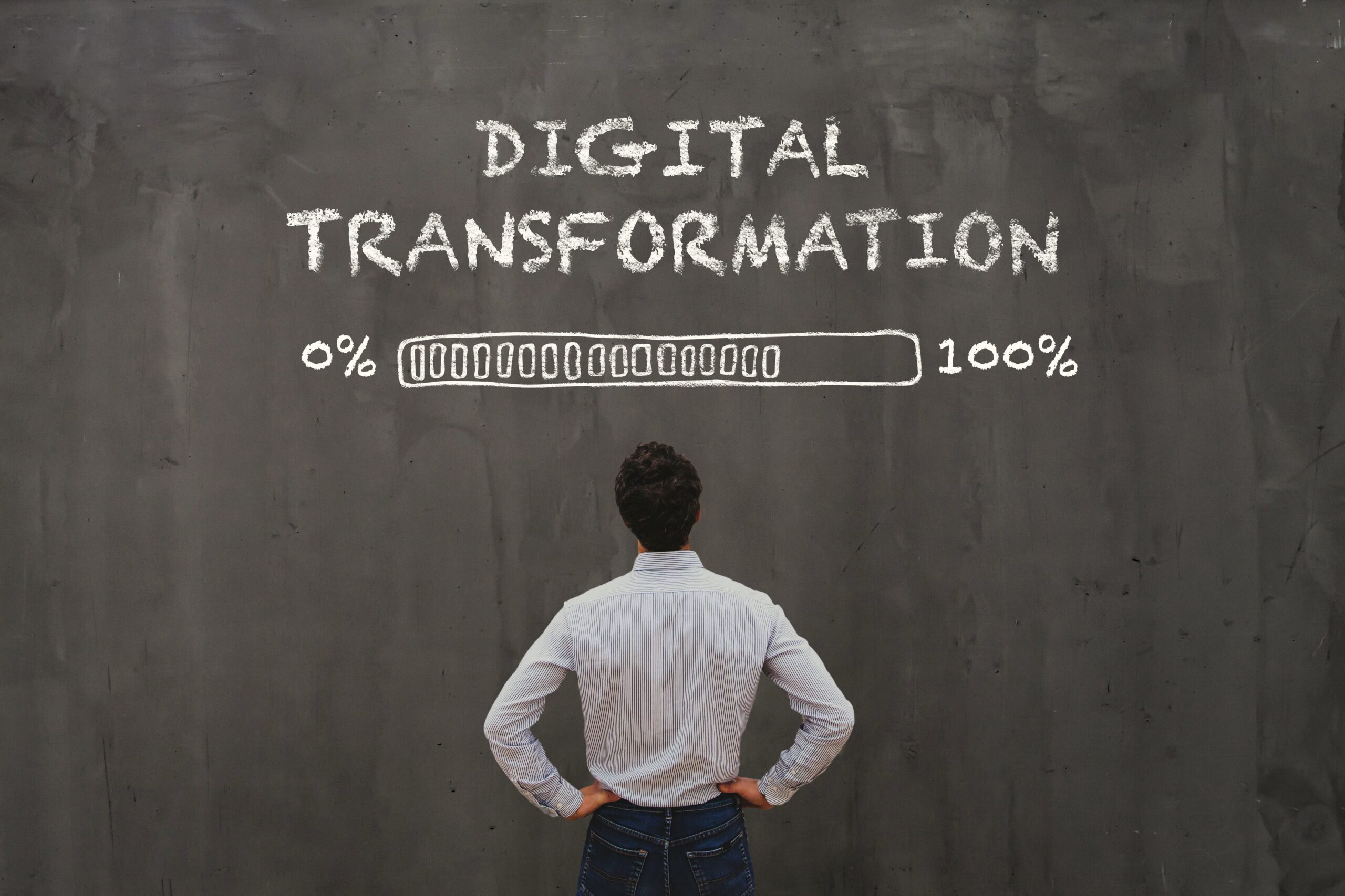 Cover image for the content on "10 mistakes in digital transformation and how to avoid them," featuring a man facing a sort of board with "digital transformation" written on it, accompanied by a progress bar loading from 0% to 100%