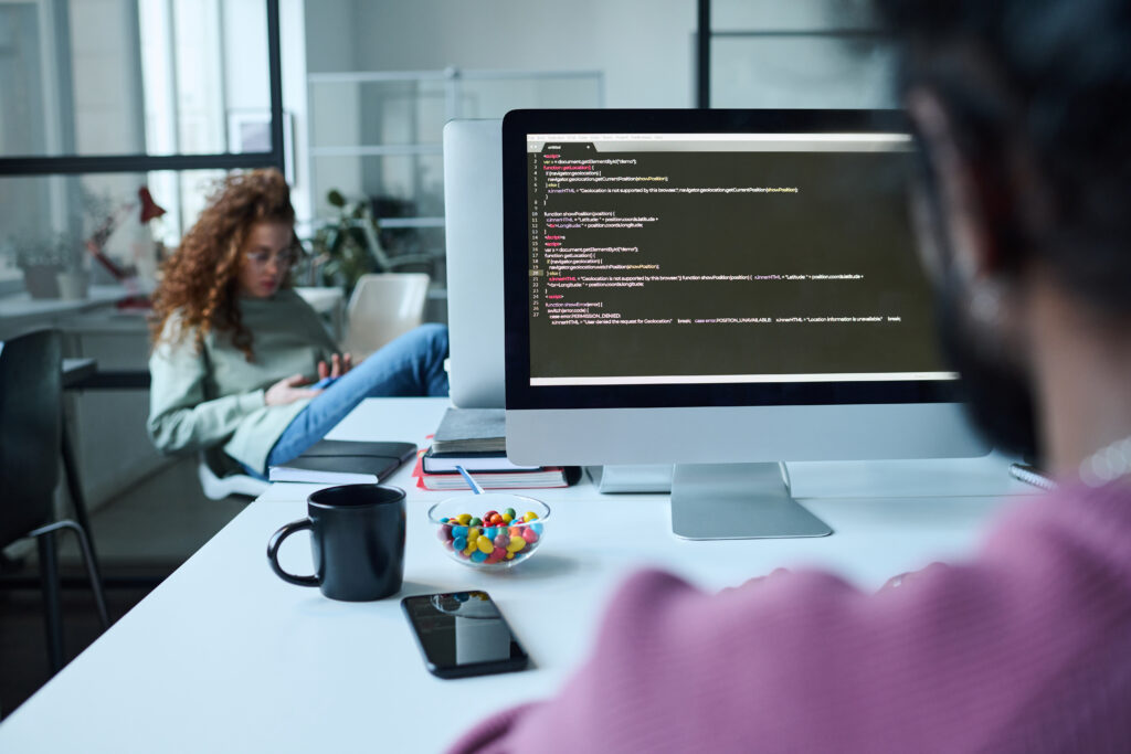 Cover image for the content on '6 Traits for Success with Developer Platforms,' featuring a man in front of a computer filled with code. In the background, a seated female developer.