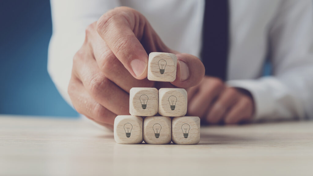 Cover image for the content "Innovation and stability in Platform Teams," featuring a person stacking small squares on top of each other, representing innovation.