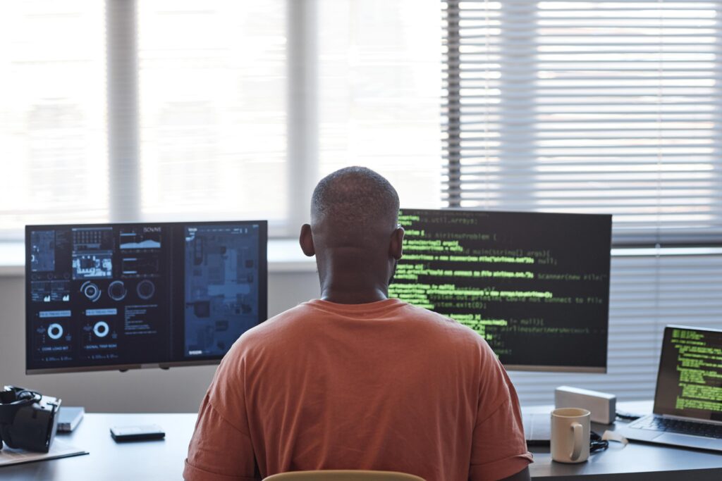 Cover image for the content on "Practices in platform engineering : comparing past and present," featuring a man in front of two computer screens filled with code.