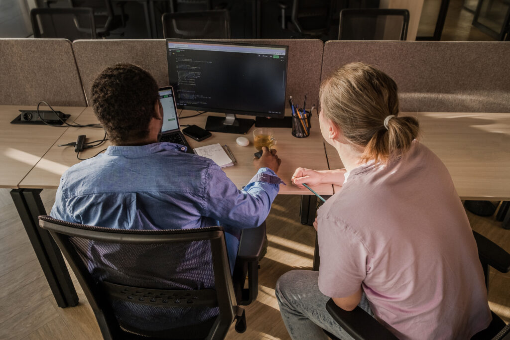 Cover image for the content on 'Debunking the myths of Internal Developer Platforms: Why critics are wrong?' featuring a man and a woman facing two computers with code on the screen.