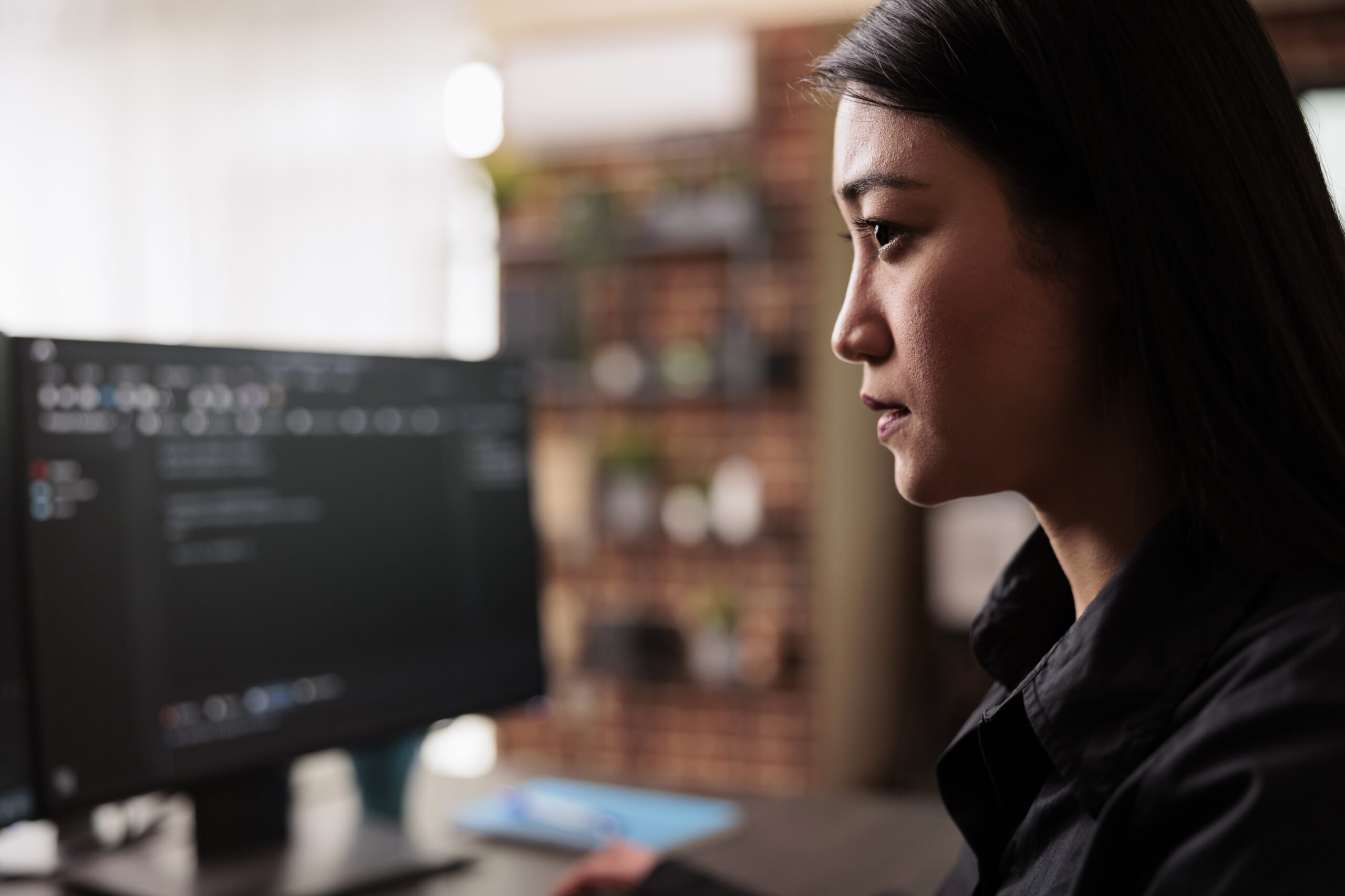 Cover image of the content about Championing Legacy Modernization in Large-scale Operations, featuring a systems engineer writing code in front of a computer screen.