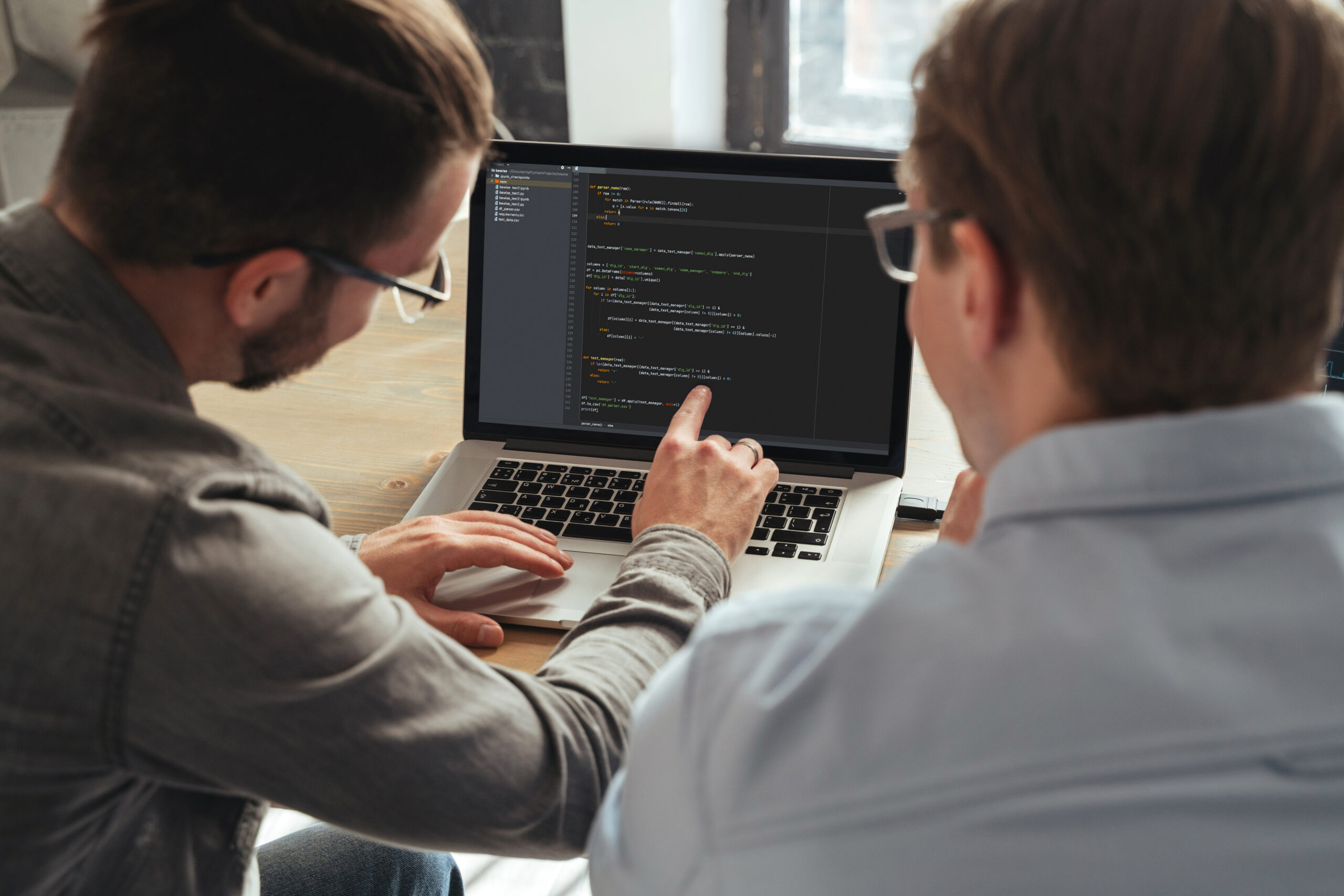 Cover image for the content on Effective Legacy Modernization, featuring two colleagues sitting in front of a computer filled with code, with one of them pointing at the screen.