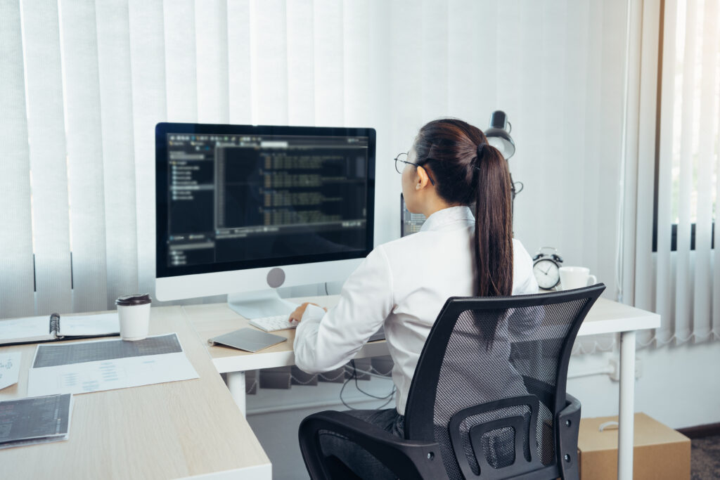 Cover image of the content on Legacy Modernization Strategies, featuring a woman developing a programming website in her office.