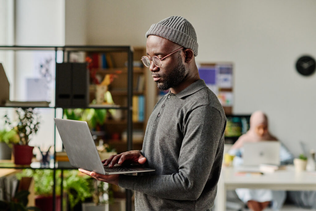 Cover image of the StackSpot AI User Study content, featuring a developer standing and using a laptop in the IT office.